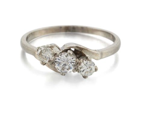 A DIAMOND THREE STONE CROSSOVER RING graduated round brilliant-cut diamonds to bypass scroll shoulders. Estimated total diamo