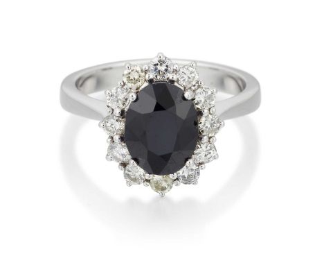 AN 18 CARAT WHITE GOLD SAPPHIRE AND DIAMOND CLUSTER RING an oval-cut sapphire within a border of round brilliant-cut diamonds