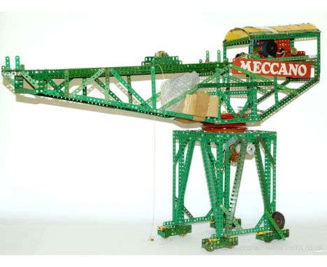 Meccano block setting crane built using parts in red, green and yellow mounted on a 4-pillar base with double sets of wheels 