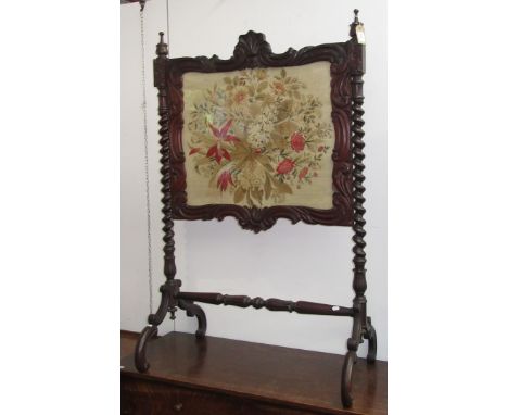 A mahogany and woolwork firescreen, 19th century, the panel depicting a large floral spray, flanked by barley twist columns, 