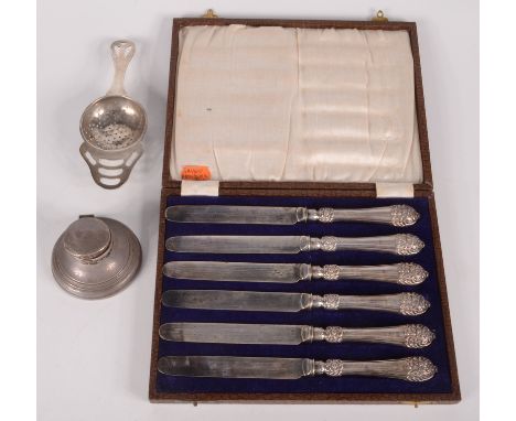A silver tea strainer, a filled silver inkwell and a set of cake knives with unusually ornate filled silver handles. 
