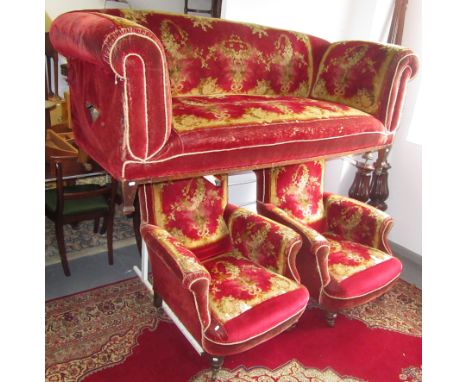 A Victorian red velvet, floral decorated upholstered three piece suite, the sofa with reclining arm, on square tapering feet,