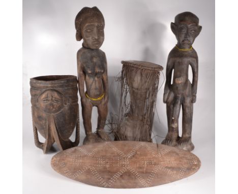 Two African carved wood fertility figures of a naked man and woman, heights 65cm and 66cm, an African oval wood shield, lengt