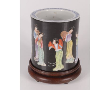 A Chinese famille noir porcelain circular brush pot, decorated with female musicians, red seal mark to base, on a huali wood 