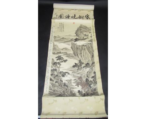 A Chinese scroll painting of a mountainous lake scene, with a figure on a bridge, a stag, houses and boats, calligraphy and r