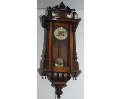 A Vienna walnut wall clock, 19th century, with three turned finials and a carved portrait of a gentleman above a 13.3cm dial 