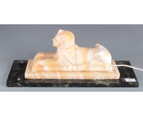 An alabaster lamp in the form of a sphinx, on a marble base, height 21cm, width 51cm, depth 17.7cm.