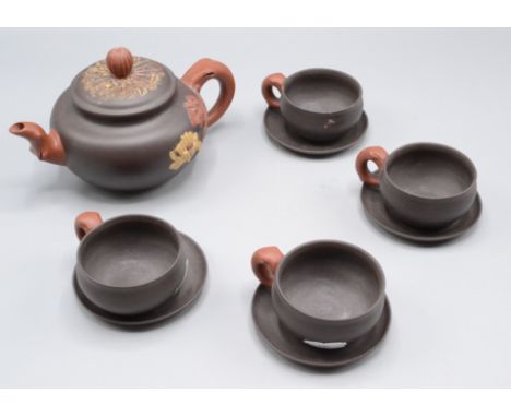 A Chinese Yixing pottery tea set, comprising a teapot and four cups and saucers, each piece with a seal mark to the base, hei