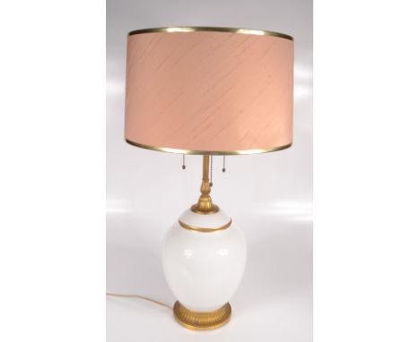 A gilt metal and milk glass table lamp, the acorn finial on a fluted column above a bulbous body on a gadrooned circular plin