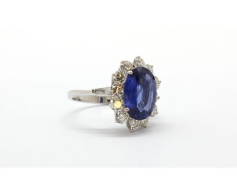 An 18ct white gold (stamped 750) ring set with a large oval cut natural Burmese sapphire surrounded by brilliant cut diamonds