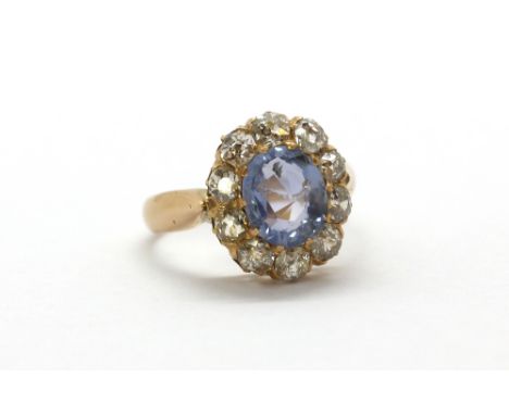 A rose metal (tested high carat gold) ring set with a natural oval cut sapphire surrounded by old cut diamonds, approx. 2.31c