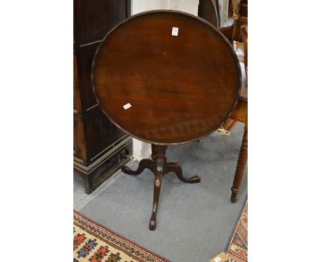 A mahogany circular tilt-top tripod table.