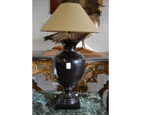 A large urn shaped black pottery table lamp.