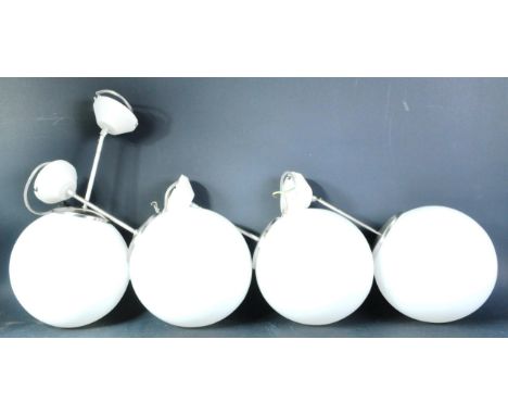 A matching set of four contemporary Art Deco style hanging lights with each having a milk glass globe shade supported by a si