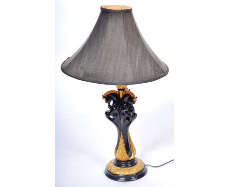 A contemporary high end designer Hollywood Regency table lamp light of faux ebony and ormolu constriction having a decorative