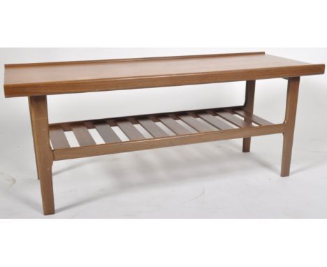 A retro vintage 1960's Danish influence teak coffee table comprising of a shaped raised edge top over a slatted magazine rack