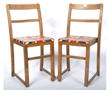 A matching pair of vintage 20th Century 1940's / 50's oak school chairs having a rail backrest with Union Jack painted seats.