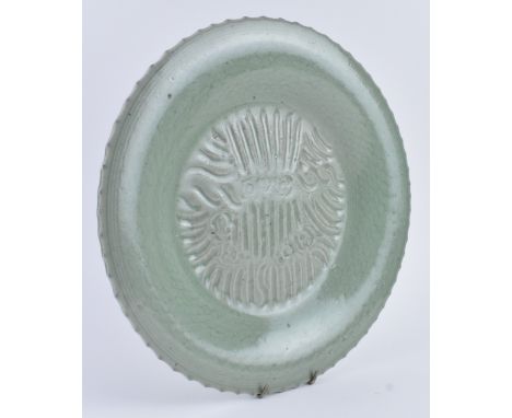 A Ming or later Longquan celadon charger. The circular ridged edge charger decorated with dragon motif and dragon scale patte