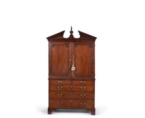 A George III mahogany linen press, late 18th century, the broken arched pediment centred by a carved finial, with blind fretw