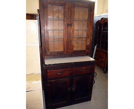 A vintage stained pine kitchen cabinet,  having lead glazed design to top, with lower pull-out shelf above two short drawers 