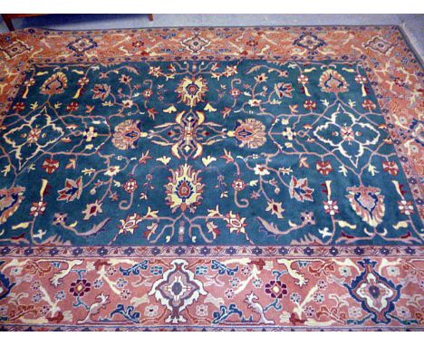 A large green ground machine knotted carpet, having central green ground florally decorated panel, surrounded by a pink groun