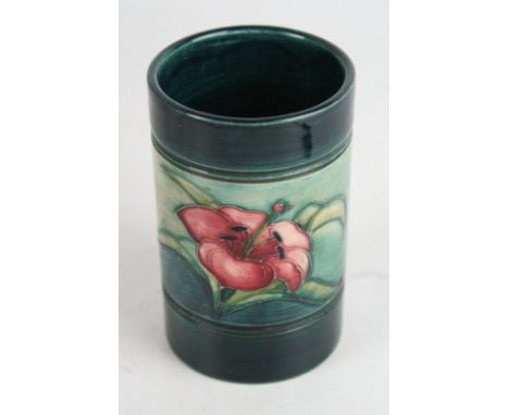A Walter Moorcroft cylindrical vaseDecorated in the 'Lily' pattern on a green and blue ground, impressed factory marks to bas