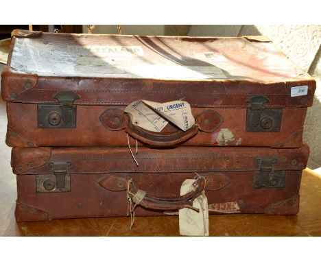 Pair of brown leather vintage suitcases with various luggage labels 