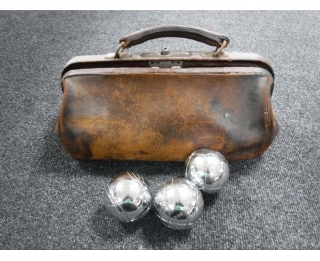 A vintage leather bag containing a set of French boules 
