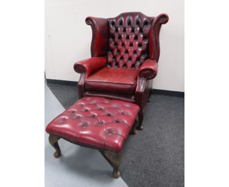 A red button leather wing back Chesterfield armchair with stool  CONDITION REPORT: Typical wrinkling to the leather on the se