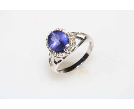 18 carat white gold tanzanite and diamond ring, the central oval tanzanite surrounded by 20 small diamonds, size N/O.