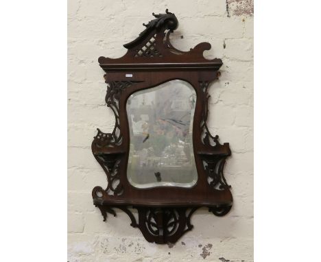 A Victorian pierced and carved mahogany hall mirror with bevel edged glass candle stands and shelf.