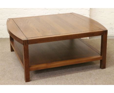 A large square formed oak coffee table with magazine shelf.