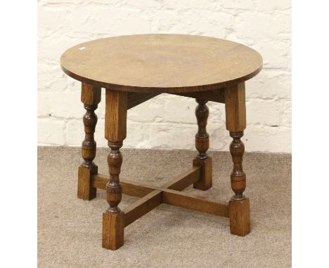 A light oak occasional table raised on turned supports and with cross stretcher.