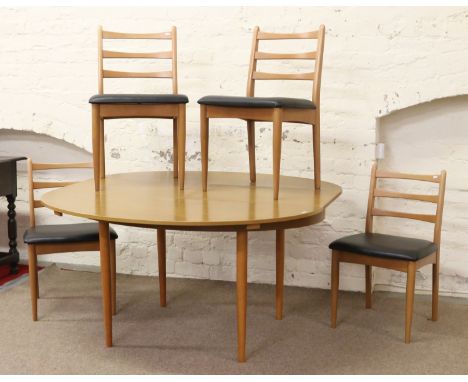 An oval retro extending dining table raised on turned supports with inbuilt leaf with four matching ladder back chairs.