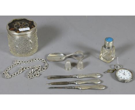 A collection of silver items; tortoise shell topped dressing table jar, fob watch, manicure set, curb chain, feeding spoon, t