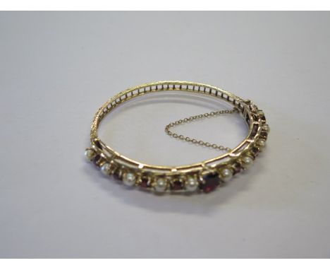 A pretty hallmarked 9ct yellow gold garnet and pearl hinged bangle with safety catch and chain, internal measurement 4.8cm x 