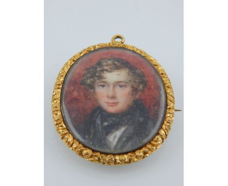 A 19th century yellow metal mounted pendant brooch, set portrait miniature, depicting a young gentleman, having glass apertur