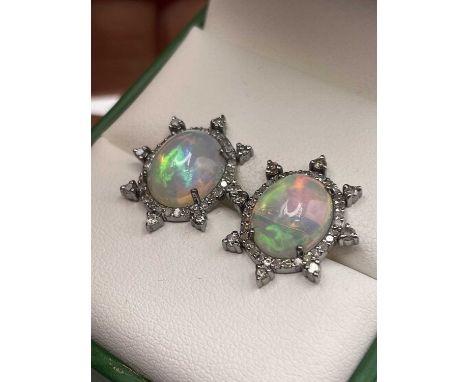 A pair of opal cabochon and diamond sunburst earrings. The opals and diamonds are set in silver with 14ct gold stems. Opals  