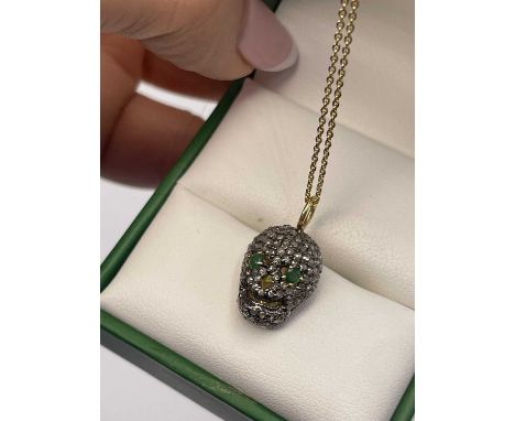A diamond set skull pendant with emerald eyes in silver gilt. Emerald weight 0.10ct, diamond weight 0.40cts.