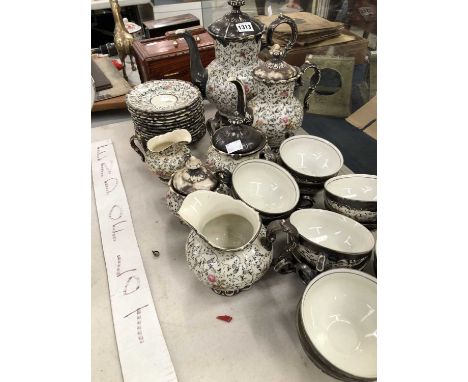 A German porcelain tea service with silvered covers above a tracery of black flowering vines