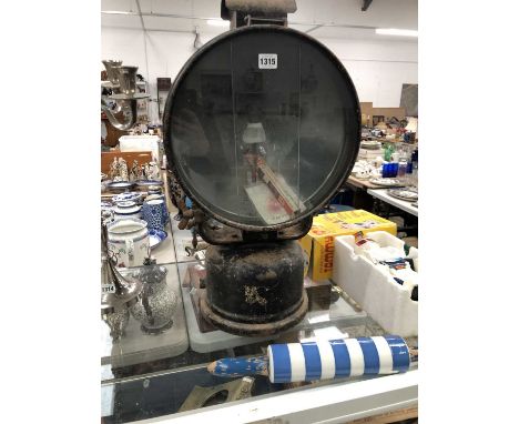 A Tilley-Hendon paraffin search light with a blackened metal hood and receiver, the lens diameter 33.5cms.