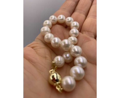 A white cultured pearl bracelet with a gold-plated silver ball clasp. Length 7.5 inches.