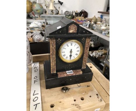 A mantel timepiece within a black slate case enhanced with mottled red marble