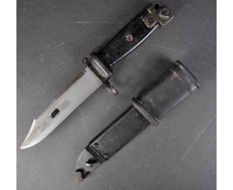 An original vintage Kalashnikov AKM rifle bayonet. The bayonet having a serrated edge to the back of the blade, black plastic