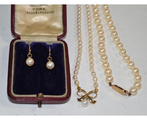 A cultured pearl necklace with a bow motif pendant, clasp stamped '375'; another cultured pearl necklace with a 9 carat gold 