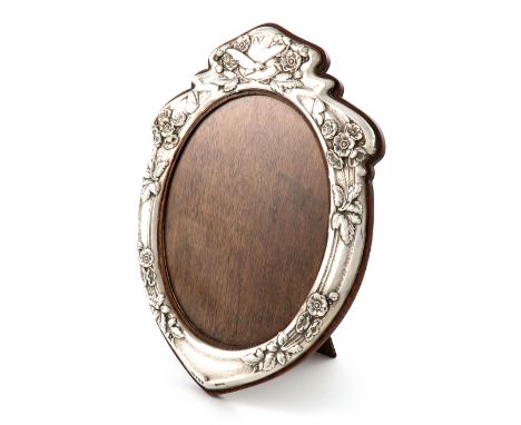 An Edwardian silver photograph frame, by Henry Charles Freeman, Birmingham 1904, shaped oval form, embossed with flowers and 