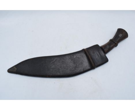 An early to mid 20th century Middle Eastern Gurkha Kukri knife / dagger with shaped wooden hilt and metal blade. Original lea