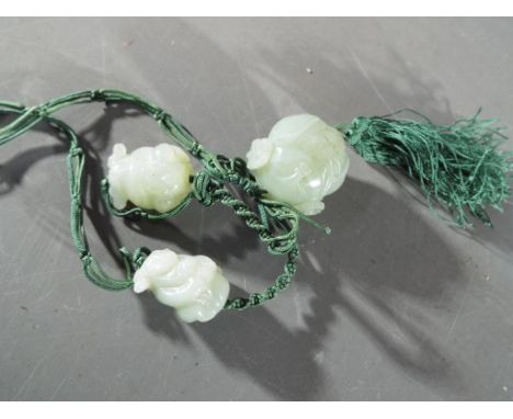A Chinese necklace comprising three carved celadon jade stones depicting a Buddha with four character marks to the front, and