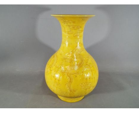 A large Chinese yellow glazed baluster vase with everted rim, decorated with incised phoenix above dragons chasing the flamin