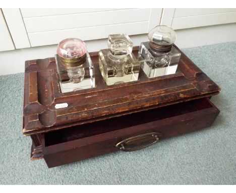 A Victorian wooden inkwell stand containing three ink wells
